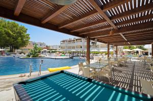 una piscina con mesas y sillas junto a una piscina en Matina Pefkos Aparthotel en Pefki Rhodes