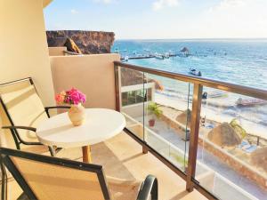 a balcony with a table and a view of the ocean at Hacienda Morelos Beachfront Hotel in Puerto Morelos