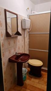 uma casa de banho com um lavatório, um WC e um espelho. em Hotel Central Praia em Tramandaí