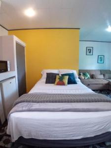 a large bed in a room with a yellow wall at blanc haus in Grecia