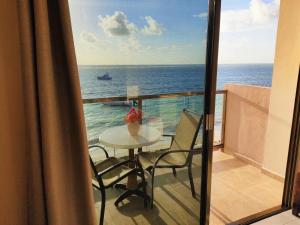 a balcony with a table and a view of the ocean at Hacienda Morelos Beachfront Hotel in Puerto Morelos