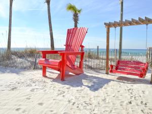 two red chairs on a swing on the beach at Boardwalk Beach Hotel in Panama City Beach