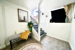 a hallway with white walls and stairs with a chair and a window at Boutique Apartment in Historic Downtown Albany in Albany