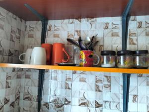 a shelf with cups and utensils on it at Magnolia Cosy 1 Bedroom Apartment-KILIFI in Kilifi