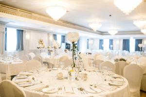 un salón de banquetes con mesas blancas y sillas blancas en Erris Coast Hotel, en Geesala