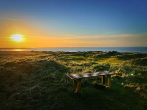 eine Bank auf einem Feld mit Sonnenuntergang in der Unterkunft Erris Coast Hotel in Geesala