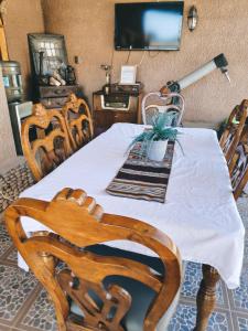a dining room table with chairs and a television at La Casa de José in San Pedro de Atacama