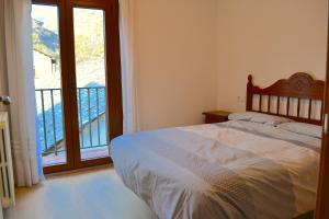 1 dormitorio con 1 cama y ventana con balcón en Apartament comfortable amb vistes i cèntric by RURAL D'ÀNEU, en Esterri d'Àneu