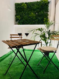 a wooden table with two wine glasses and a chair at Stadiumapartament in Santa Cruz de Tenerife