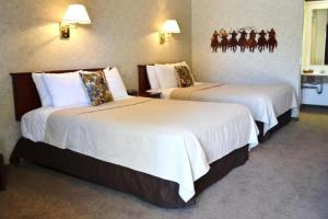um quarto de hotel com duas camas com lençóis brancos em Covered Wagon Motel Lusk WY em Lusk