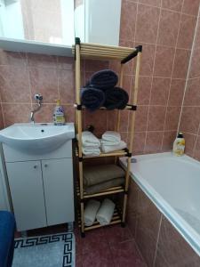a bathroom with a towel rack next to a sink and a tub at Apartman Ferhadija Saraj in Sarajevo