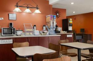 2 Tische und Stühle in einem Restaurant mit orangefarbenen Wänden in der Unterkunft Super 8 by Wyndham Prestonsburg in Prestonsburg