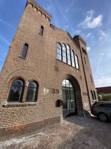 a large brick building with a glass door at De Kerck - bijzonder overnachten in Middelburg