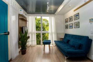 sala de estar con sofá azul y ventana en Casa Container Incrível no Campeche, 2 hóspedes SUL91, en Florianópolis