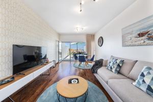 a living room with a couch and a tv at Praia Mar by OCvillas in Albufeira