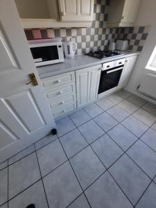 a kitchen with white cabinets and a tile floor at River View Two Bed Room Luxury Apartment in Thamesmead