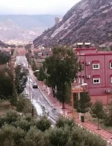 uma rua da cidade com edifícios e árvores e uma montanha em Hôtel Titrit em Tafraout