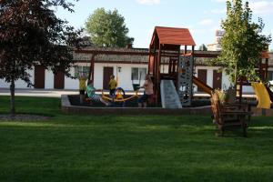 3 personnes assises sur une aire de jeux dans un parc dans l'établissement Covered Wagon Motel Lusk WY, à Lusk