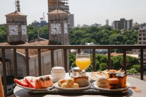 une table avec deux assiettes de nourriture et un verre de jus d'orange dans l'établissement Mato Grosso Palace Hotel, à Cuiabá