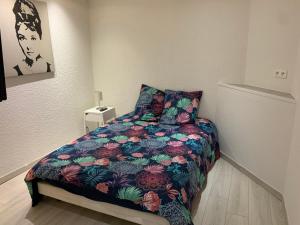 een slaapkamer met een bed met een kleurrijk dekbed bij Appartement 1er Etage 42m2 hyper centre ville / parking gratuit in Riom