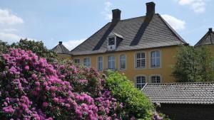 a yellow house with pink flowers in front of it at Hotel Schloss Diepenbrock in Bocholt