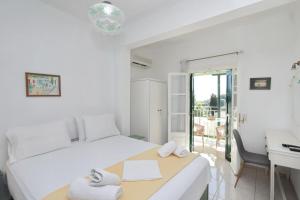 a white bedroom with a bed and a desk at Pelagos in Stafylos