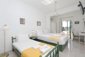 2 Betten in einem Zimmer mit einem Tisch und einem Schreibtisch in der Unterkunft Pelagos in Stafylos