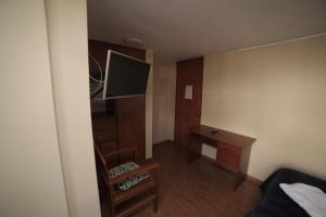 Habitación pequeña con cama, escritorio y TV. en Hostal Premier Arequipa, en Arequipa