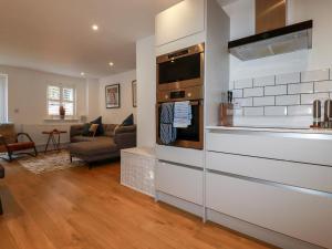 a kitchen with a stove and a living room at Little Reef in Newquay