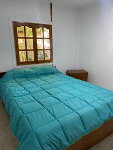 1 dormitorio con cama azul y ventana en CABAÑAS MZA RANCH en Las Compuertas