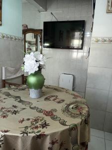 una mesa con un jarrón verde con flores. en Departamento Loló en Mendoza