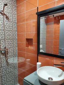 ein Bad mit einem Waschbecken und einem Spiegel in der Unterkunft Helga’s Sunset apartment in Tirana