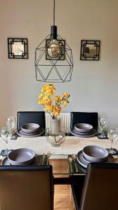 a dining room table with plates and a vase of flowers at Modern 3BR House For Contractors in Stockingford