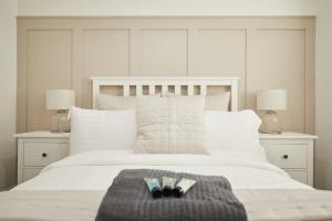 a white bed with two books and two lamps at Luxurious and Modern 3 Bed townhouse with Parking in Norwich