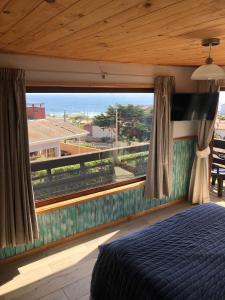 1 dormitorio con cama y ventana grande en Hostal F en El Quisco