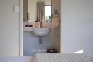 a bathroom with a sink and a mirror at Vineyard Apartment in Tutukaka