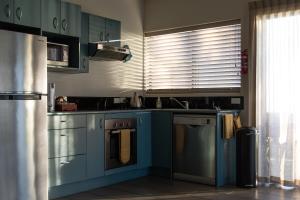 a kitchen with blue cabinets and a dishwasher at Vineyard Apartment in Tutukaka