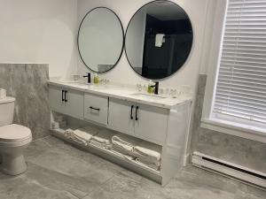a bathroom with a white sink and two mirrors at Hotel Bedford in Goderich