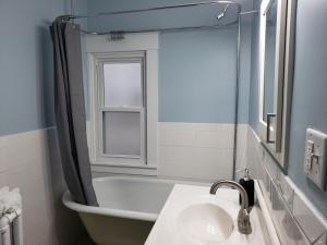 La salle de bains est pourvue d'une baignoire, d'un lavabo et d'un miroir. dans l'établissement The Uptown Oasis, à Minneapolis