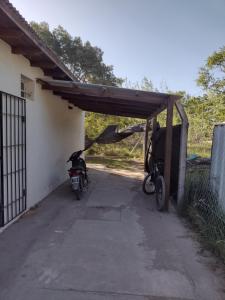 una motocicleta estacionada bajo un cobertizo al lado de una casa en Culoteland en Necochea