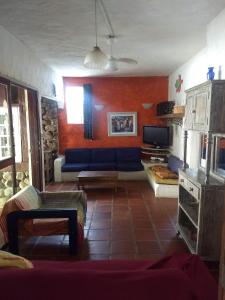 a living room with a blue couch and a tv at Casas de 1, 2 e 4 quartos-100m da praia- com AC-WIFI-Estac in Camburi