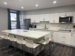 a kitchen with a large white counter and chairs at Hotel Bedford in Goderich