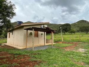 a small house in a field next to a fence at Chalé da Picareta in São Roque de Minas