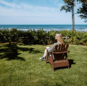 una mujer sentada en una silla en la hierba en Ocean Crest Resort en Moclips