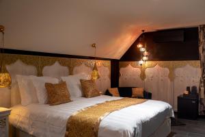 - une chambre avec un grand lit blanc et des oreillers en or dans l'établissement B&B 1001 nacht, à Zonhoven