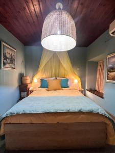 a bedroom with a large bed with a large chandelier at DandyVillas-Vintage Cottage House-Pelion-Argalasti-Kallithea in KallithÃ©a