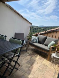 a patio with a couch and a table on a balcony at Maison coeur de village Ramatuelle in Ramatuelle