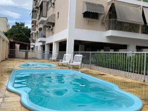 a swimming pool with two chairs and a building at Hospedagem Canal do Bora Viajar in Rio de Janeiro