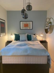 a bedroom with a bed with blue sheets and two lamps at Kongens Apartment St Joseph in Kristiansand