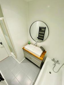 La salle de bains blanche est pourvue d'un lavabo et d'un miroir. dans l'établissement Le doux refuge - 50m2 flat in the heart of Orleans, à Orléans